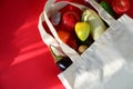 Reusable shopping textile bag full of groceries, fresh fruits and vegetables purchased from the store on red background Royalty Free Stock Photo