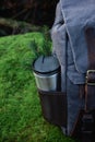 Reusable stainless steel travel thermo mug in the pocket of the backpack outdoors.