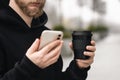 Reusable stylish bamboo cup and smartphone in the hands of a man, close-up. Royalty Free Stock Photo