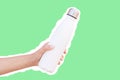 Reusable thermo water bottle in hand, isolated with white contour on green.