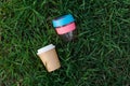 Reusable travel plastic keep cup and cardboard disposable non-recyclable glass on grass background. glass takeaway mug