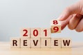 Hand flip wood cube change year 2018 to 2019 and the word REVIEW on wooden block on wood table Royalty Free Stock Photo