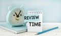 Review Time word on notebook with clock and blue pencil . Review and assessment concept. Royalty Free Stock Photo