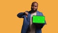 Reviewer shows thumbs down sign gesturing holding green screen laptop