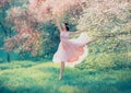 Revived porcelain doll in flying pink dress dancing in flowering spring forest, tender lady with dark hair in bright Royalty Free Stock Photo