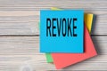 REVOKE - word on note paper on wooden light background