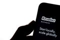 Revolut Business app on the smartphone hold by a silhouette of a hand in front of white screen. No alterations and editing to the