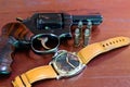 Revolver with bullets on brown wooden tables and clocks