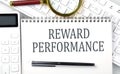 REWARD PERFORMANCE . Text on notepad with calculator and keyboard,business concept Royalty Free Stock Photo