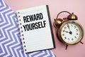 Reward Yourself text written on notepad with alarm clock Royalty Free Stock Photo