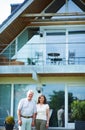 The rewards of a generous nest egg. Cropped portrait of a mature couple standing hand-in-hand in front of their home. Royalty Free Stock Photo