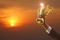 Reword of work . business hand in suit holding golden trophy with sun rise abstract multi color background ,  business concept Royalty Free Stock Photo