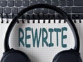 REWRITE -word on white notepad with keyboard and headphone background