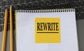 REWRITE - word on a yellow piece of paper on the background of a laptop with a notebook and a pen
