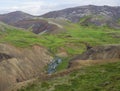 Reykjadalur valley with hot springs river, lush green grass meadow, rocks and hills with geothermal steam. South Iceland