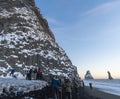 Reynisfjara black sand beach at sunset and the basalt formations covered in snow and illuminated by the last rays of the sun from