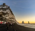 Reynisfjara black sand beach at sunset and the basalt formations covered in snow and illuminated by the last rays of the sun from