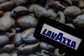 Rheinbach, Germany 1 October 2021, The brand logo of `Lavazza` on the display of a smartphone in front of a picture with roaste