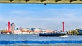 A Rhine Barge on the Nieuwe Maas river with the Willems Bridge in the background viewed from under the Erasmus Bridge in Rotterdam