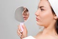 Rhinoplasty. A young beautiful woman holds a mirror with aquiline nose. Comparison of results before and after plastic Royalty Free Stock Photo