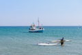 Windsurfer and fishing boat near coast of Rhodes island.