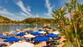 In a bay on the island of Rhodes, holidaymakers relax under parasols