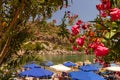 In a bay on the island of Rhodes, holidaymakers relax under parasols