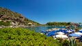 In a bay on the beautiful island of Rhodes, holidaymakers relax under parasols