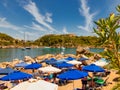 In a bay on the island of Rhodes, holidaymakers relax under parasols