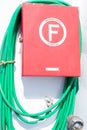 Rhodes, Greece, June 6, 2019: Red colored box and rolled green fire hose on white wall on the Dodekanisos express boat