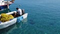 Man in a fishing boat in a marina on Rhodes island. Free-living Sea turtles swim around.