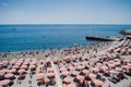 Rhythm of red umbrellas and tourists on a sunny beach in Genoa, Italy. Royalty Free Stock Photo