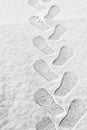 Rhythmic boot prints on thin white snow in winter recede into the distance, vertical frame, ribbed protector, winter concept Royalty Free Stock Photo