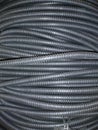 Ribbed black plastic pipes are twisted in concentric circles.