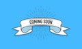 Ribbon with the inscription Coming Soon. Old vintage ribbon banner in engraving style and light rays on the blue Royalty Free Stock Photo