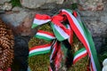 Ribbon with national colours of Hungary tied up to the flower tribute standing near to the old castle wall in Mukachevo, Ukraine.