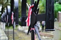 Ribbon with national colours of Poland tied up to the old cross on the cemetery. History concept.