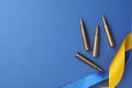 Ribbons in colors of national Ukrainian flag and bullets on blue background, flat lay. Space for text Royalty Free Stock Photo