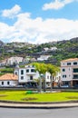 Ribeira Brava, Madeira, Portugal - Sep 9, 2019: City center on a vertical picture with palm trees. Buildings on the hills in the