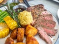 Ribeye beef steak medium to well done grilled served with corn, pototoes and asparagus