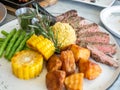 Ribeye beef steak medium to well done grilled served with corn, pototoes and asparagus