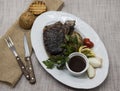 Ribeye steak from marble beef meat with vegetables and barbecue sauce. Served on a plate of black stone with fork and knife . Royalty Free Stock Photo