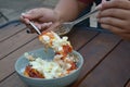 Rice bowl with chicken katsu and tomato sauce and mozzarella cheese scooped with spoon and fork. Blurred background.