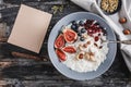 Rice coconut porridge with figs, berries, nuts, dried apricots and sheet of paper on rustic wooden background