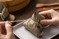 Rice dumpling zongzi eating - Young Asian woman is eating Chinese traditional food on wooden table at home for Dragon Boat Royalty Free Stock Photo