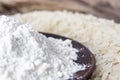 Rice flour in a bowl near the heap of white rice on old boards. Jasmine rice for cooking Royalty Free Stock Photo