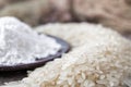 Rice flour in a bowl near the heap of white rice on old boards. Jasmine rice for cooking Royalty Free Stock Photo