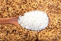 Rice grain in a wooden spoon and forming a background. Royalty Free Stock Photo