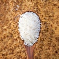 rice grain in a wooden spoon and forming a background. Royalty Free Stock Photo