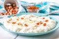 Rice milk porridge with nuts and raisins in a blue dish on a white wooden table.